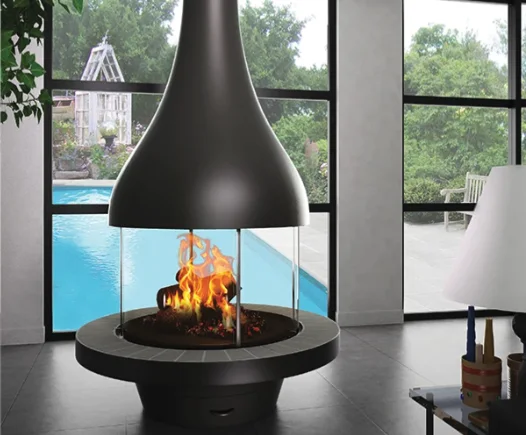 A JC Bordelet fireplace with a wide glass front, garden framed behind it