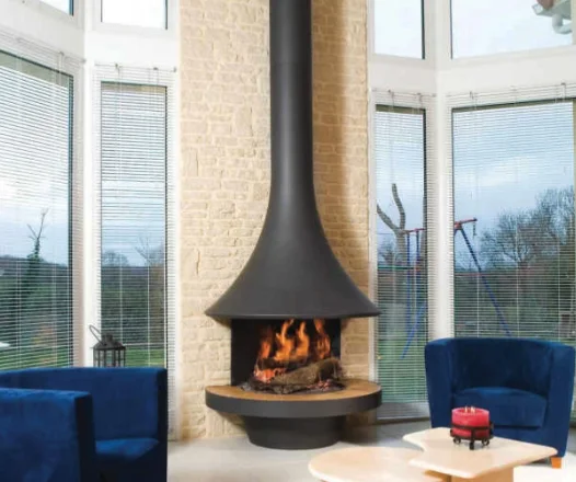 A suspended fireplace lit beside a blue sofa and floor-to-ceiling glass