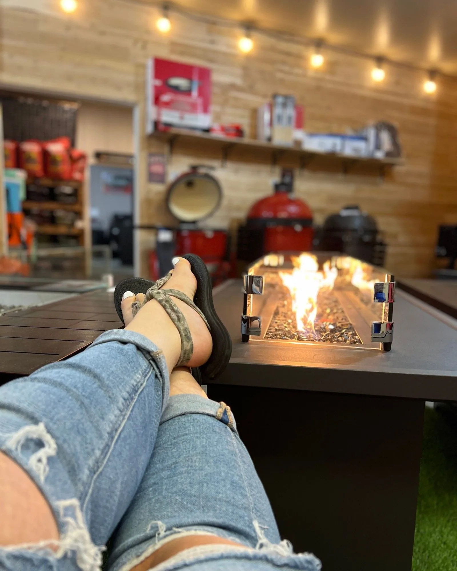 Feet up beside a burning fire table in the showroom's backyard display