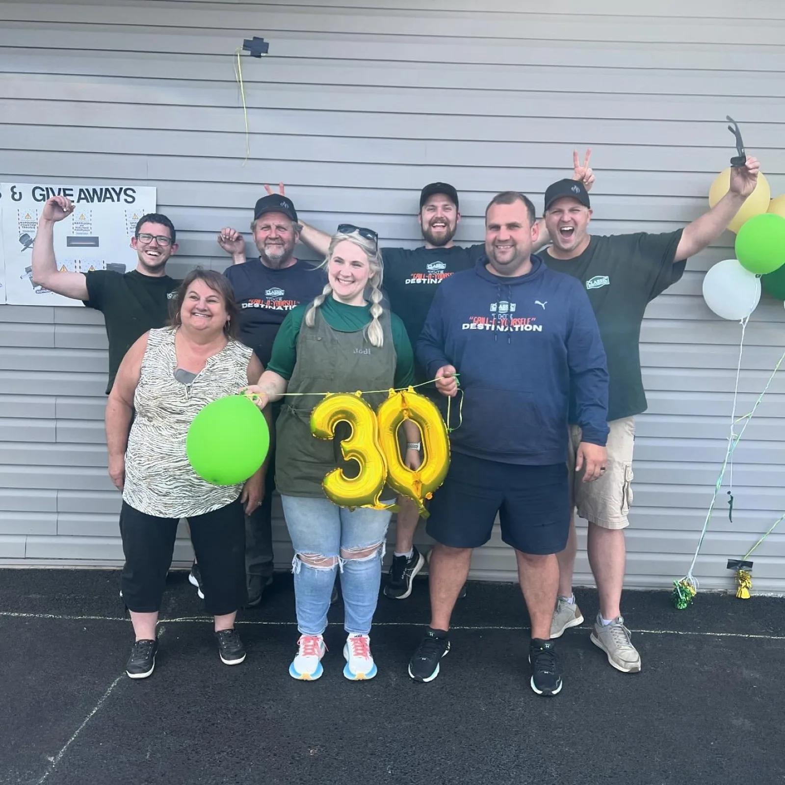 The Classic Stoves & Fireplaces crew celebrating outside the shop with gold 30 balloons
