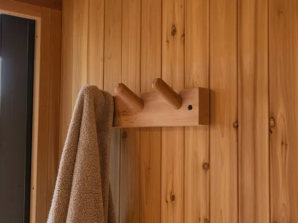 Natural red cedar towel rack holding a towel on a sauna wall